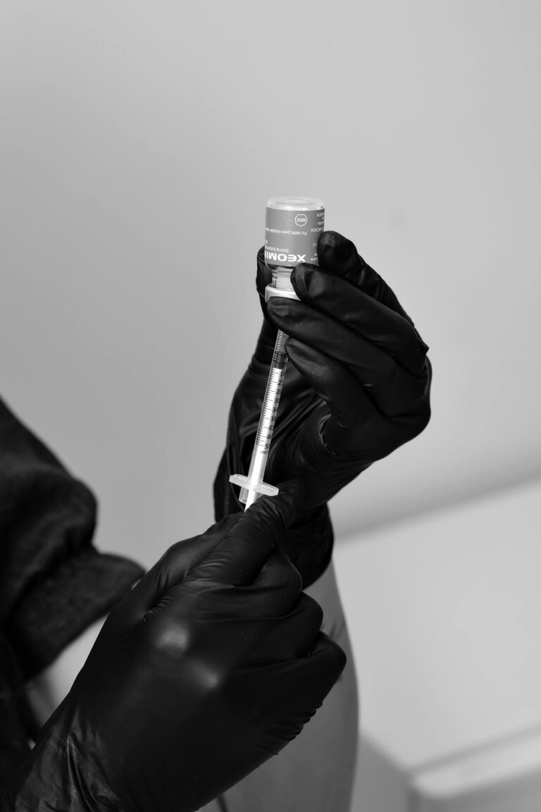 Black and white image of healthcare professional preparing syringe in Belo Horizonte clinic.